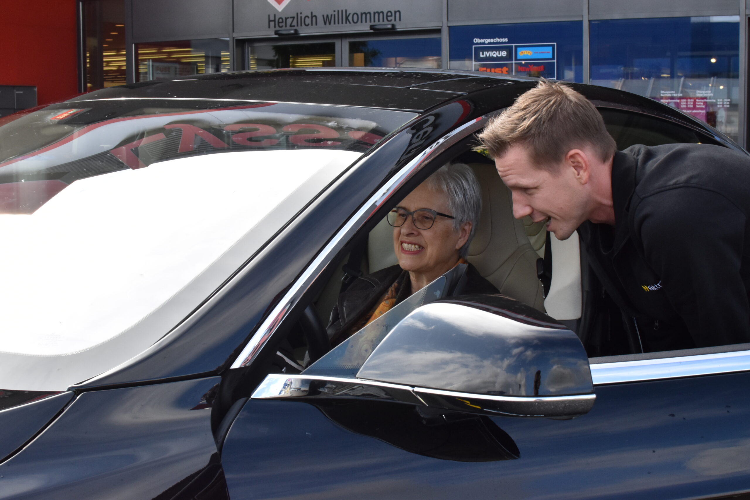 Matthias Ostermeier, Fachspezialist für Energielösungen bei Elektra, erklärt der glücklichen Wettbewerbsgewinnerin Frau Schori, wie der Tesla zu bedienen ist.