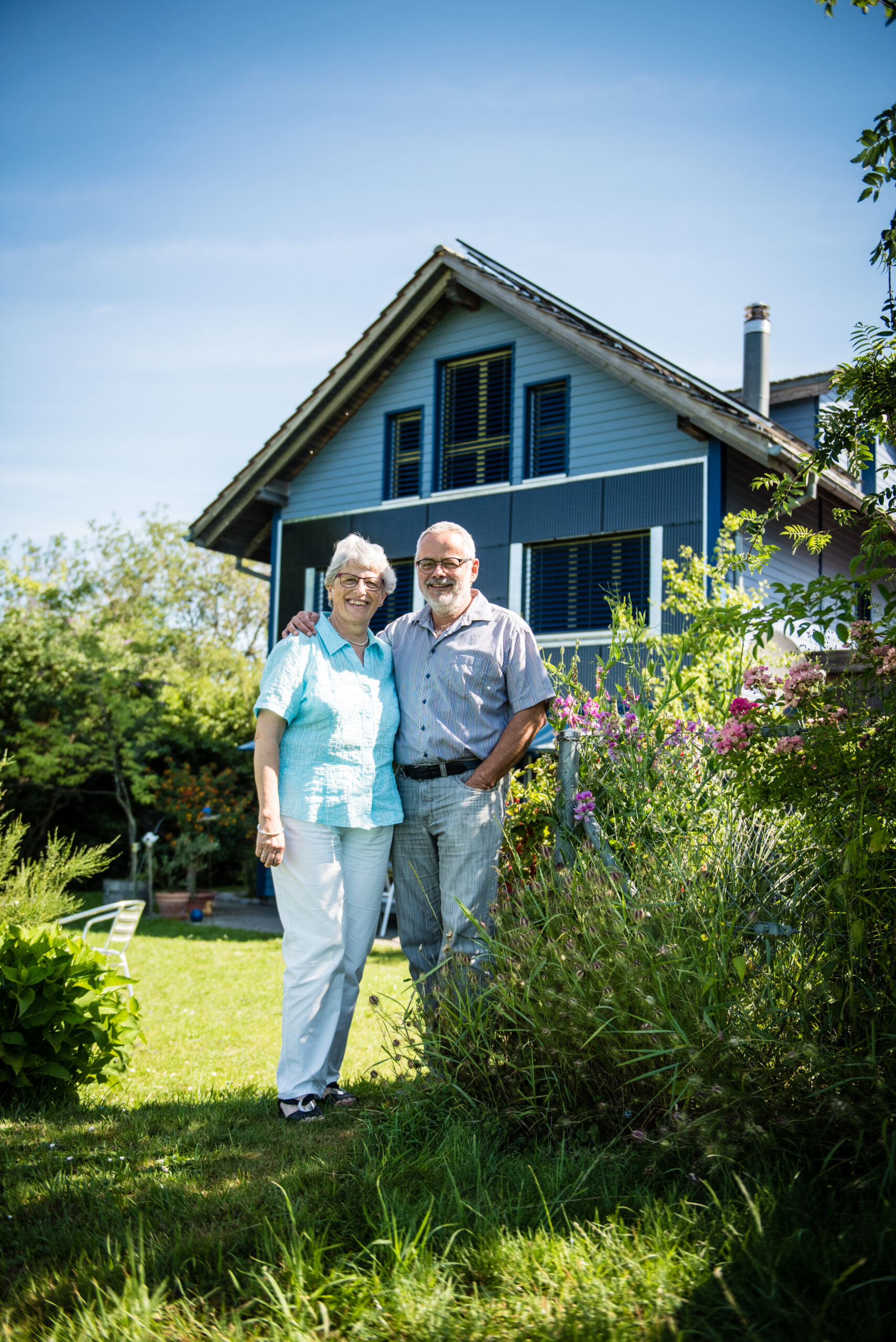 Die Rubins stehen vor ihrem Blue House, aus dem sie ein kleines Krafwerk gemacht haben mit Solaranlage und Stromspeicher im Keller