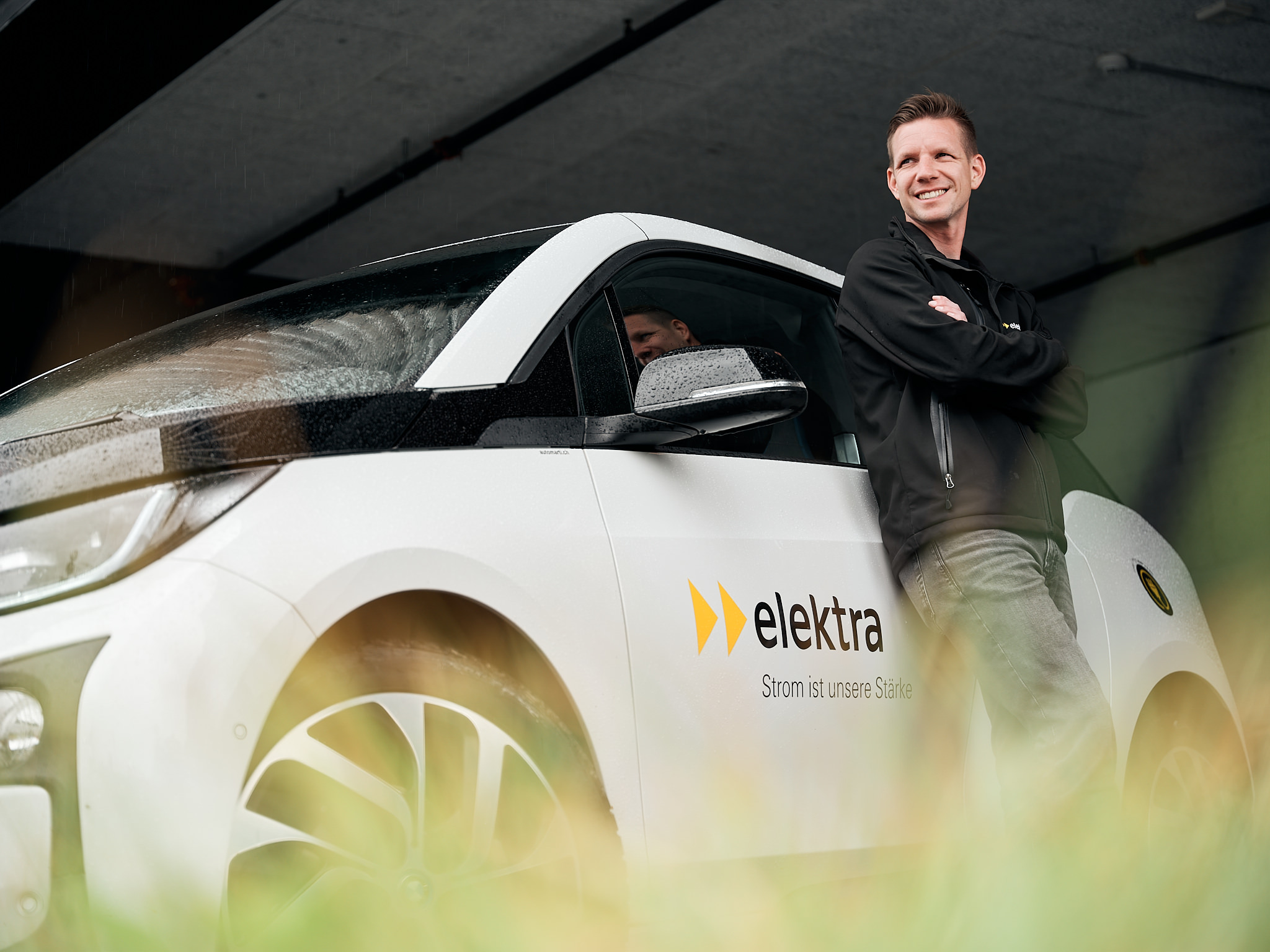 Matthias Ostermeier, Fachspezialist für Elektromobilität bei Elektra, posiert vor einem BMW i3.