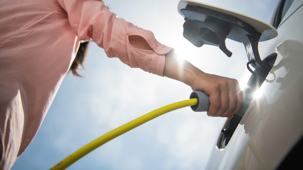 Ein Mann lädt ein Elektroauto auf.