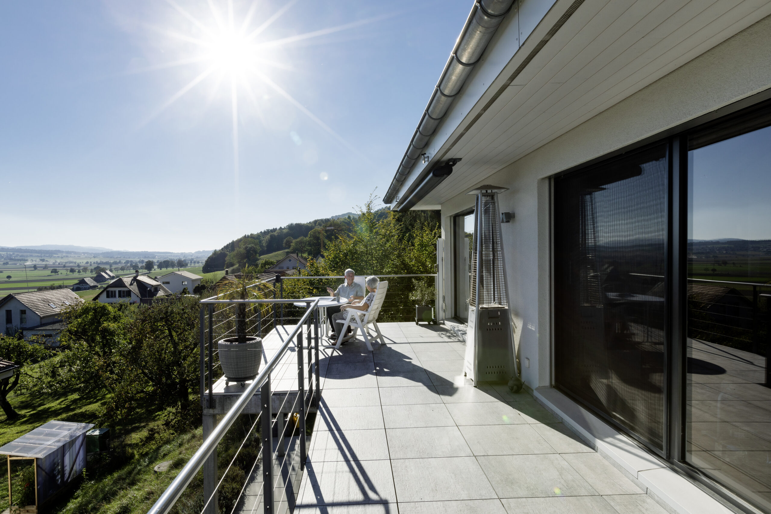 Zwei Menschen sitzen auf einer Terrasse.