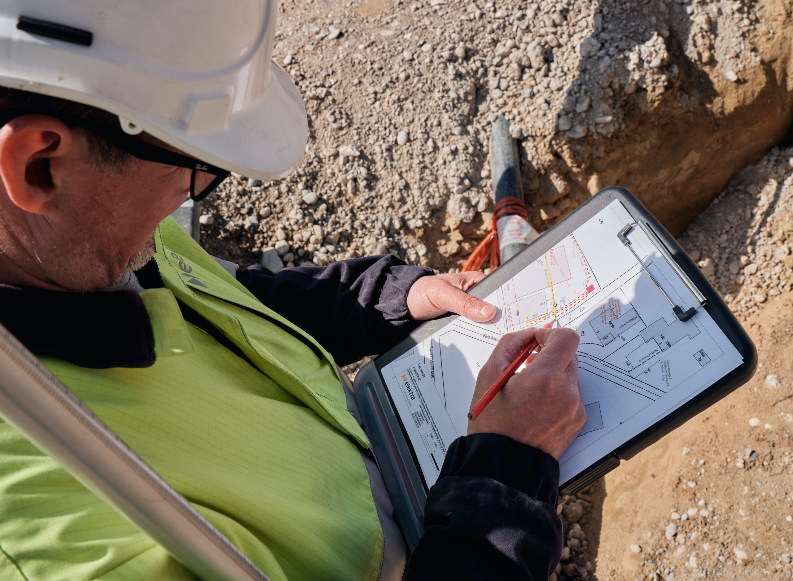 Michael Müller, Projektleiter Netze bei Elektra, ist auf der Baustelle und zeichnet eine Stromleitung auf einem Katasterplan ein.