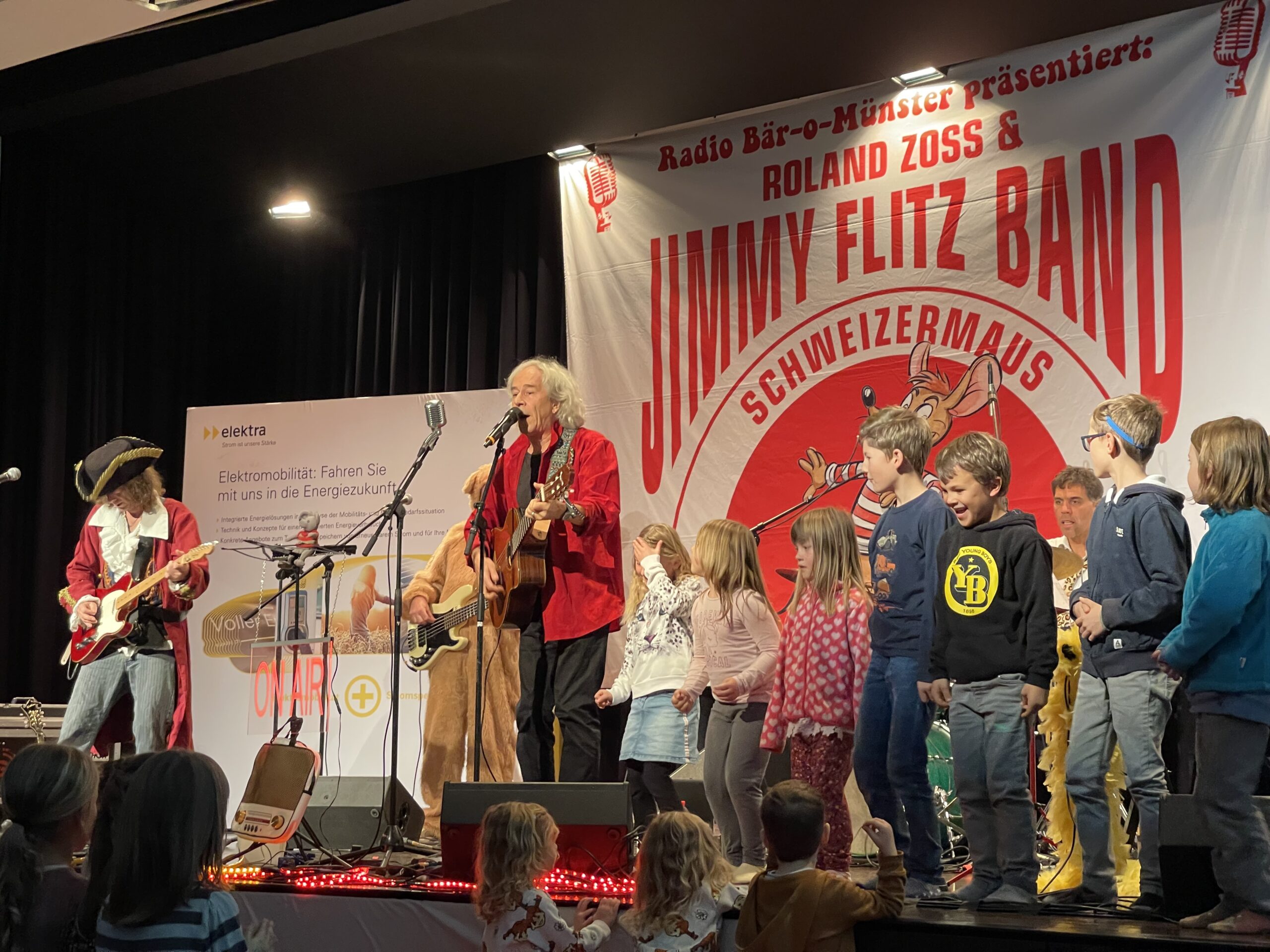 Die Bühne ist voll mit Roland Zoss und JimmyFlitz Band und einer Horde singender und tanzender Kinder am Elektra Kinderevent 2021.