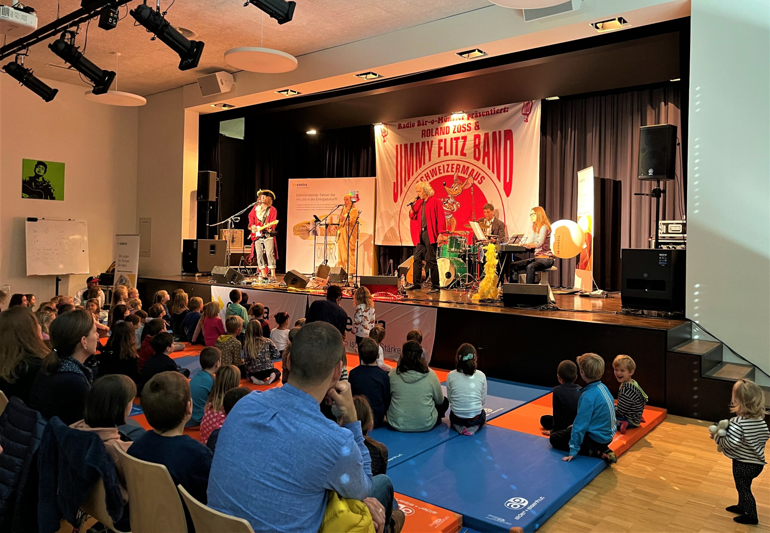 Während die Roland Zoss & JimmyFlitz Band die Bühne des diesjährigen Elektra Kinderevents 2021 in Hindelbank rockt, feiern die Kinder auf Turnmatten mit.