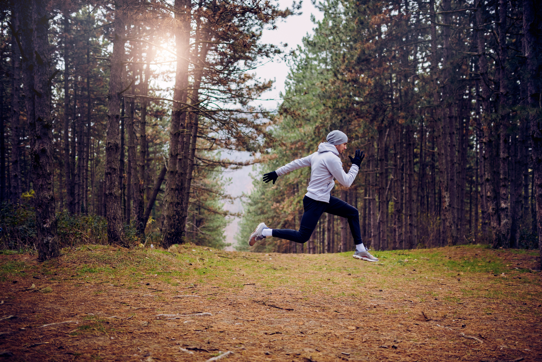 Ein junger Mann sprintet voller Energie durch einen Wald.
