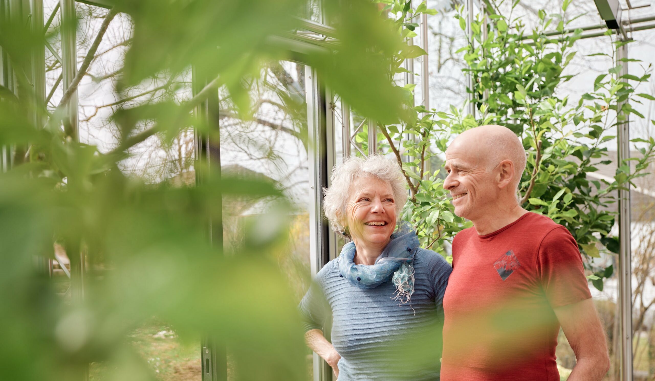 Christine und Christian Jenni stehen im Wintergarten und sind umringt von ihren Pflanzen. Die Natur und Umwelt ist dem Ehepaar wichtig. Deshalb haben sie ihre Solaranlage mit einer Salzbatterie kombiniert. Sie konnten damit ihren Eigenverbrauch deutlich steigert und versorgen sich heute zur Hälfte mit selbst produzierter Solarenergie.