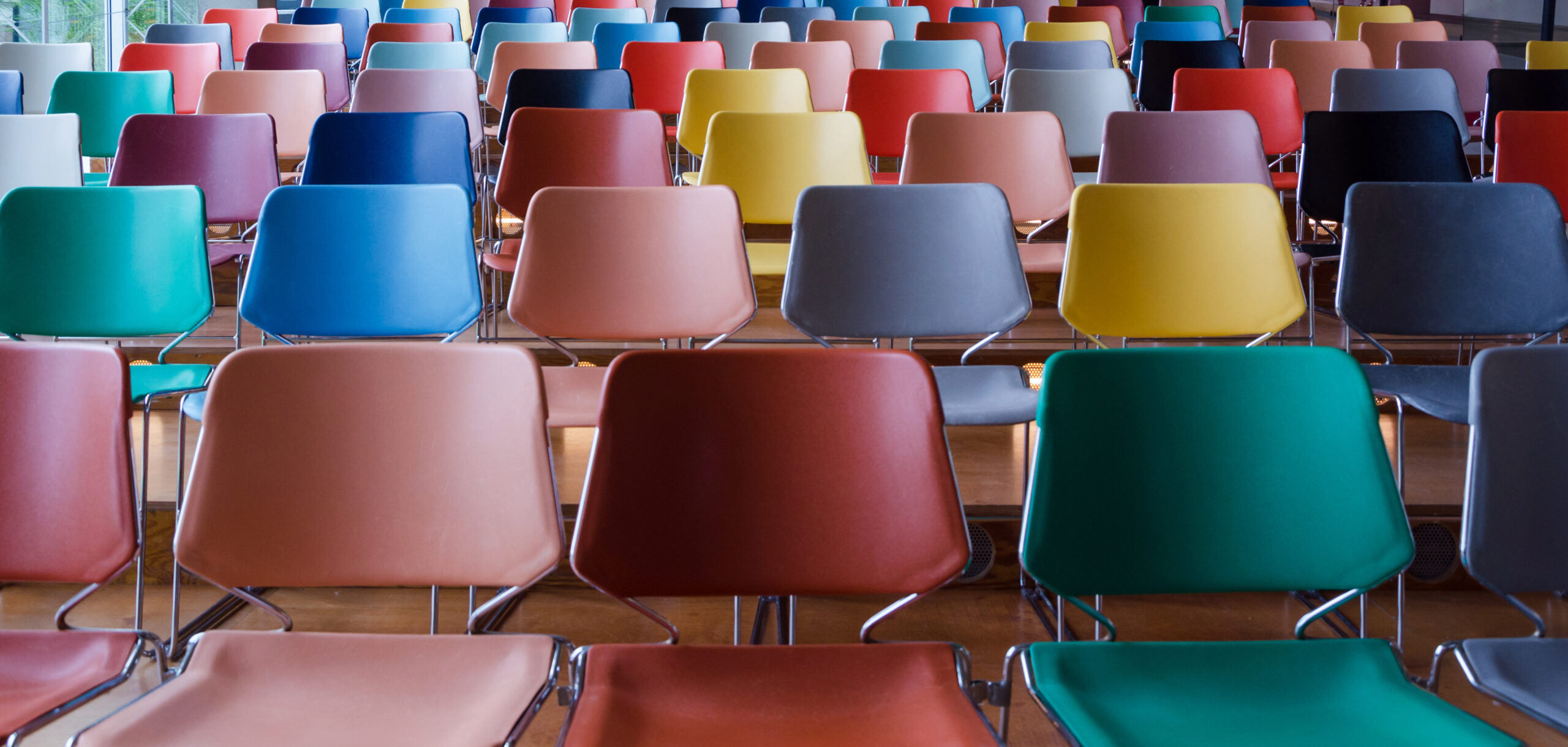 Mehrere farbige Stuhlreihen in einem Hörsaal