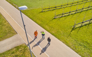 Elektra Projektleiter Michael Müller steht mit zwei Gemeindevertretern bei einer Strassenlampe, einem Kandelaber, und diskutiert eine mögliche Lösung, um die Strassenbeleuchtung sicher und effizient zu unterhalten.